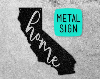 May include: Black metal sign shaped like the state of California with the word "home" written in white cursive lettering. The sign has a textured surface and is labeled "METAL SIGN".