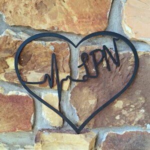 May include: Black metal heart-shaped wall decor with a stylised EKG line and the word "LPN" inside.