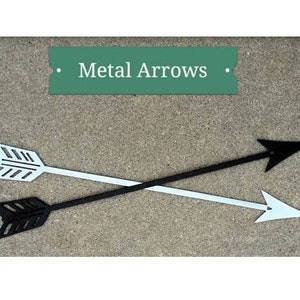 May include: Two metal arrows, one black and one white, are crossed over each other. The arrows are on a gray concrete surface. The text "Metal Arrows" is on a green banner above the arrows.