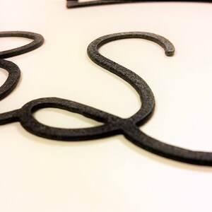 May include: Close-up of a black metal word art piece that spells out the word "Best".