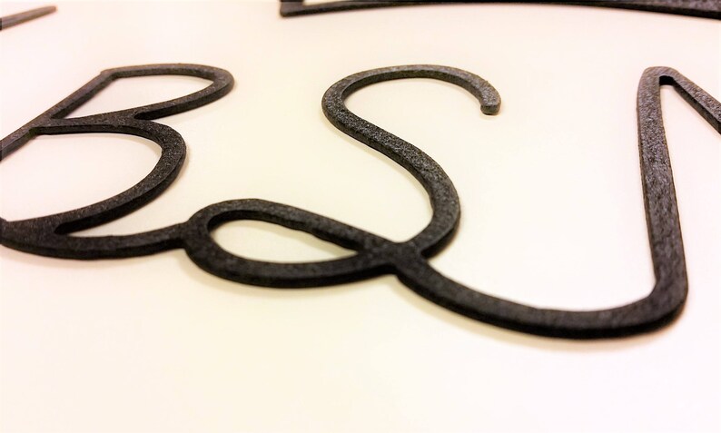 May include: Close-up of a black metal word art piece that spells out the word "Best".
