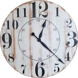 K&ouml;nnte beinhalten: Eine wei&szlig;e Holzuhr mit schwarzen r&ouml;mischen Ziffern als Stundenmarkierungen und schwarzen Zeigern. Das Zifferblatt der Uhr hat einen abgenutzten Look mit sichtbarer Holzmaserung. Das Zifferblatt der Uhr hat auch schwarze Markierungen f&uuml;r die Minuten.