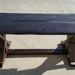 Farmhouse-style coffee table with distressed stained trestle legs.   Reclaimed wood, Fixer upper style.
