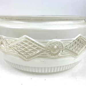 May include: A white glass light fixture shade with a decorative clear glass band featuring diamond and circle patterns. The shade has a rounded shape with a ribbed lower edge.