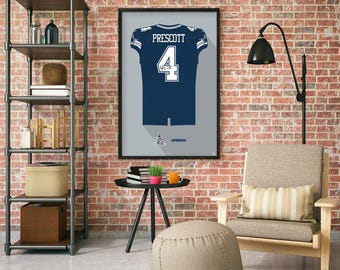 Può includere: Opera d'arte incorniciata con una maglia da football blu navy con il nome "Prescott" e il numero "4" in bianco. La maglia presenta dettagli bianchi e argento. L'opera è presentata su uno sfondo grigio con effetto ombra.