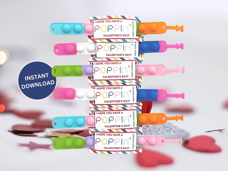 May include: A stack of Valentine's Day gifts featuring colorful pop-it toys and accompanying cards. The cards read "I HOPE YOU HAVE A POPPIN' VALENTINE'S DAY!" and "FROM MORGAN". The pop-it toys are in various colors, including pink, blue, green, and orange.