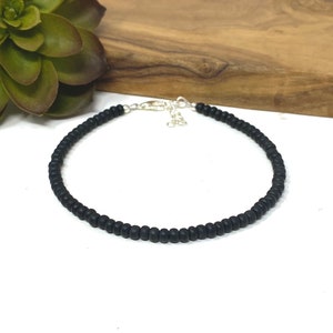May include: A black beaded anklet with a silver clasp.