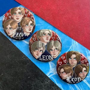 May include: Three circular badges with illustrations of a character with different hairstyles and expressions. The badges have a red background with white hearts. The name "Leon" is written on each badge.