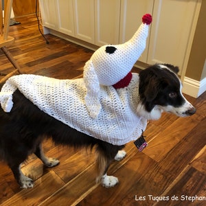 May include: A brown and white dog wearing a white crocheted ghost costume with a red nose and black eyes. The dog is standing on a wooden floor. The text "Les Tuques de Stephanie" is visible in the bottom right corner of the image.