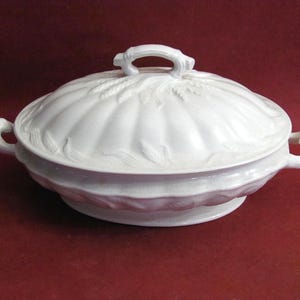 May include: White ceramic serving dish with a lid. The dish has a scalloped edge and a handle on the lid. The lid is decorated with wheat stalks. The dish has two handles on the sides.