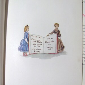 May include: Two dolls, one in a blue and white dress and the other in a brown dress, stand on either side of an open book. The book is open to a page with the text "To all the Children and Dolls who come to the Christmas Party" on the left side and "and to Rosabelle for helping out" on the right side.
