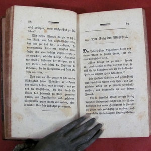 May include: An open antique book with aged, off-white paper pages featuring printed German text. The left page is numbered 88 and the right page is numbered 89, with the heading 14. Der Sieg der Wahrheit visible on the right side of the book.