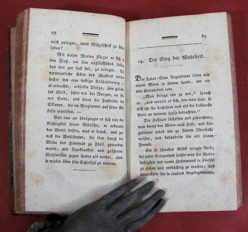May include: An open antique book with aged, off-white paper pages featuring printed German text. The left page is numbered 88 and the right page is numbered 89, with the heading 14. Der Sieg der Wahrheit visible on the right side of the book.