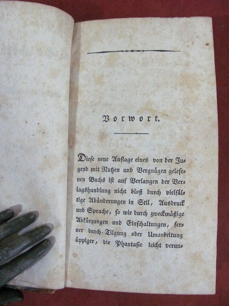 May include: An open antique book page with aged, off-white paper featuring dark brown foxing spots. The text is printed in a black Fraktur typeface, beginning with the heading Vorwort, followed by a paragraph of German text starting with Diese neue Auflage.