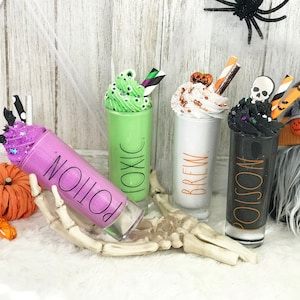 Può includere: Quattro bicchieri a tema Halloween con panna montata e decorazioni. I bicchieri sono etichettati "Pozione", "Tossico", "Birra" e "Veleno".