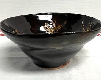 Handmade studio pottery bowl with a dark , earthy glaze and a floral design signed