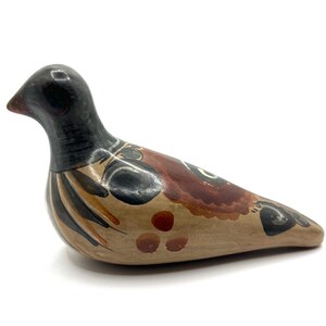 May include: A ceramic bird figurine with a black head and neck, and a body painted with brown, tan, and black details. The bird is in a resting position, with its beak slightly open. The figurine is a decorative item.