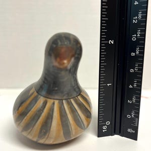 May include: A handcrafted ceramic bird figurine. The bird has a dark gray head and body with a lighter, patterned design in shades of tan and gray around the base. The figurine is approximately 3 inches tall.