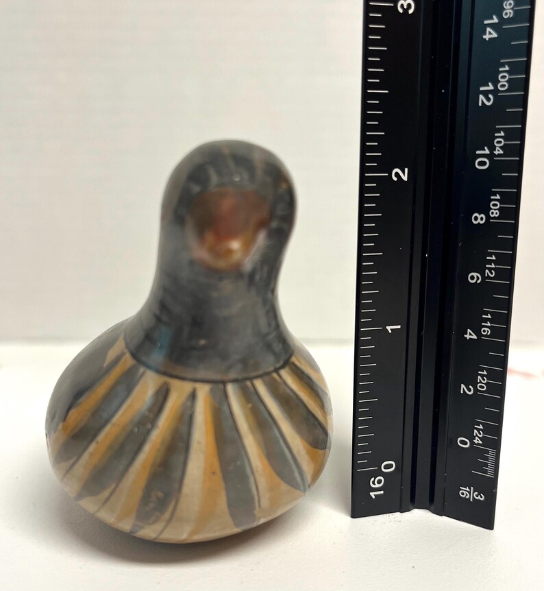 May include: A handcrafted ceramic bird figurine. The bird has a dark gray head and body with a lighter, patterned design in shades of tan and gray around the base. The figurine is approximately 3 inches tall.