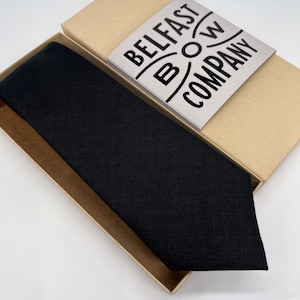 Puede incluir: Una corbata de lino negra en una caja marr&oacute;n con el texto "BELFAST BOW COMPANY" en la caja.