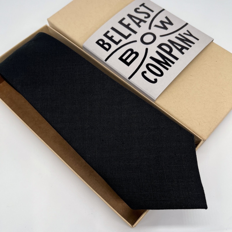 Puede incluir: Una corbata de lino negra en una caja marr&oacute;n con el texto "BELFAST BOW COMPANY" en la caja.