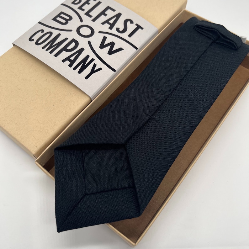 Puede incluir: Una pajarita negra en una caja de cart&oacute;n marr&oacute;n con el texto "BELFAST BOW COMPANY" impreso en la tapa de la caja.