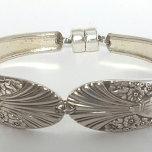 May include: A silver bracelet made from a vintage spoon with a floral design. The bracelet has a magnetic clasp.