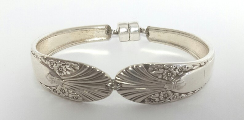 May include: A silver bracelet made from a vintage spoon with a floral design. The bracelet has a magnetic clasp.