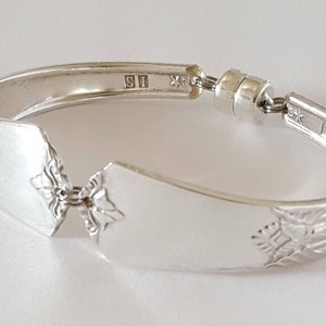 Peut inclure: Bracelet en argent fabriqu&eacute; &agrave; partir d'une cuill&egrave;re r&eacute;utilis&eacute;e avec un motif d&eacute;coratif et un fermoir magn&eacute;tique. La cuill&egrave;re porte les marques "S1" et "SK" au dos.