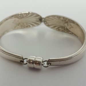 May include: Silver spoon bracelet with a magnetic clasp. The bracelet is made from two spoons that have been bent into a circle and joined together with a magnetic clasp.