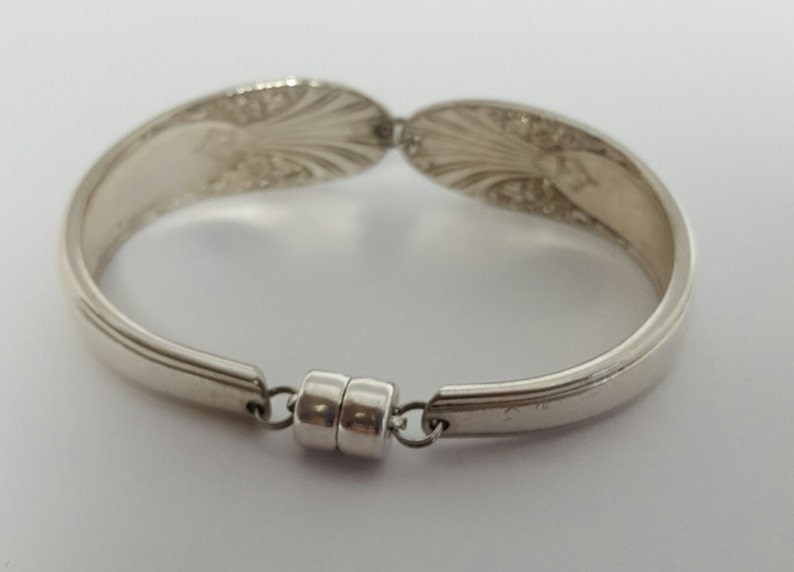 May include: Silver spoon bracelet with a magnetic clasp. The bracelet is made from two spoons that have been bent into a circle and joined together with a magnetic clasp.
