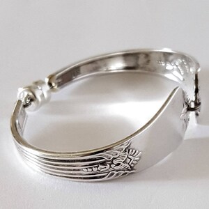 Peut inclure: Bracelet en argent fait &agrave; partir d'une cuill&egrave;re courb&eacute;e avec un motif floral. Le bracelet se ferme avec un fermoir.