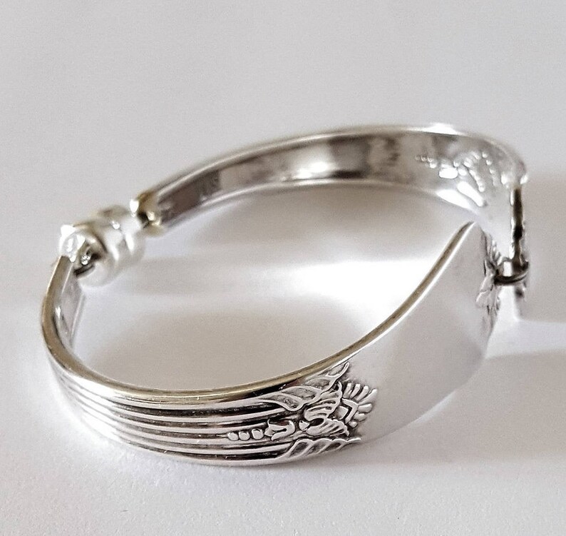 Peut inclure: Bracelet en argent fait &agrave; partir d'une cuill&egrave;re courb&eacute;e avec un motif floral. Le bracelet se ferme avec un fermoir.