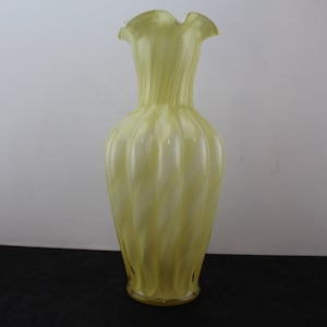 May include: A yellow glass vase with a fluted design. The vase has a wide mouth and a narrow base.