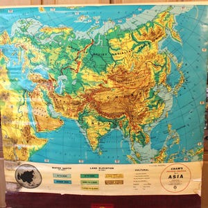 May include: A vintage physical-political map of Asia, featuring a detailed depiction of the continent's topography and political boundaries. The map uses a color-coded system to represent land elevation and water depth, with text labels for countries and geographical features. The map is labeled "CRAM'S PHYSICAL-POLITICAL ASIA."
