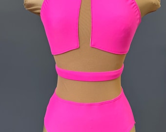 May include: A vibrant, hot pink dance costume displayed on a mannequin. The two-piece set features a halter top with a keyhole cutout and high-waisted bottoms. The design includes a mesh panel and a band around the waist.