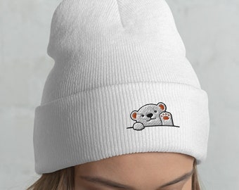 May include: White beanie with a small embroidered image of a white bear peeking out from behind a white wall. The bear has brown eyes and a brown nose.