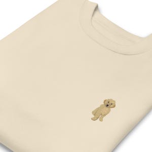 Może przedstawiać: Kremowa bluza z małym haftowanym obrazkiem golden doodle.