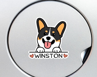 May include: A black and white cartoon corgi dog with orange ears peeking over a white banner with the text "WINSTON" and two pink hearts on either side.
