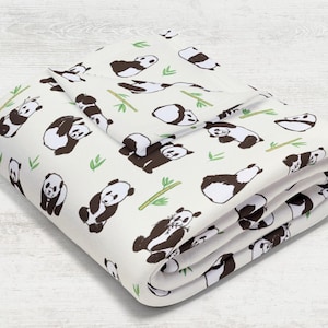 May include: A white fleece blanket with a repeating pattern of black and white pandas and green bamboo shoots.