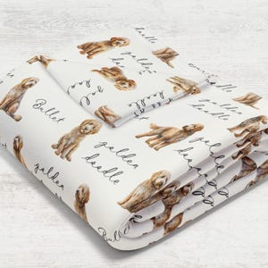 May include: White bedding set featuring watercolor illustrations of Golden Doodle dogs. The set includes a folded blanket and a pillowcase, both adorned with the words "Golden Doodle" and "Bullet" in a handwritten font.