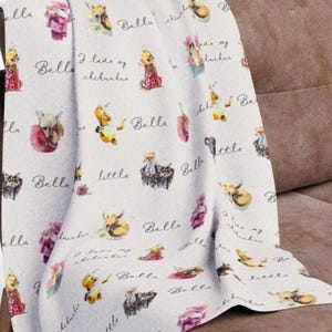 May include: A white fabric baby blanket with a repeating pattern of watercolor illustrations of foxes wearing clothes and the text "Bella I love my chihuahuas Bella little Bella".