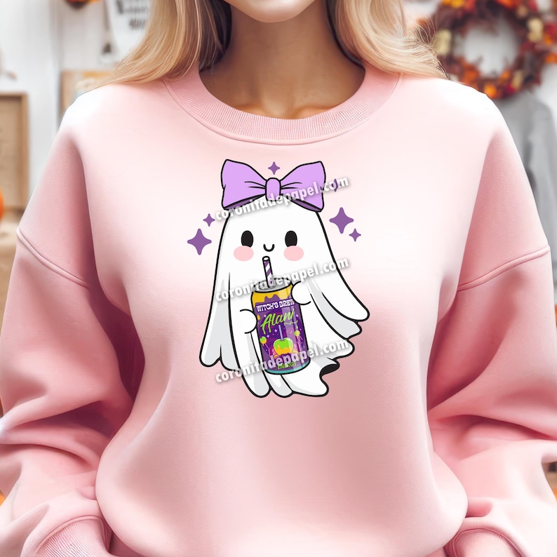 May include: A light pink sweatshirt featuring a cartoon ghost with a purple bow and holding a drink. The drink has the text "Witch's Brew Alan" on it. The ghost is surrounded by purple stars.