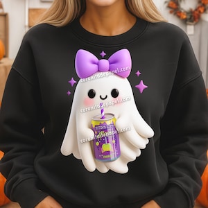 Op de afbeelding: Zwart sweatshirt met een cartoon spookontwerp. Het spook heeft een paarse strik en houdt een blikje "Witch's Brew" met een rietje vast. Het ontwerp bevat paarse steraccenten. Een leuk, Halloween-thema.