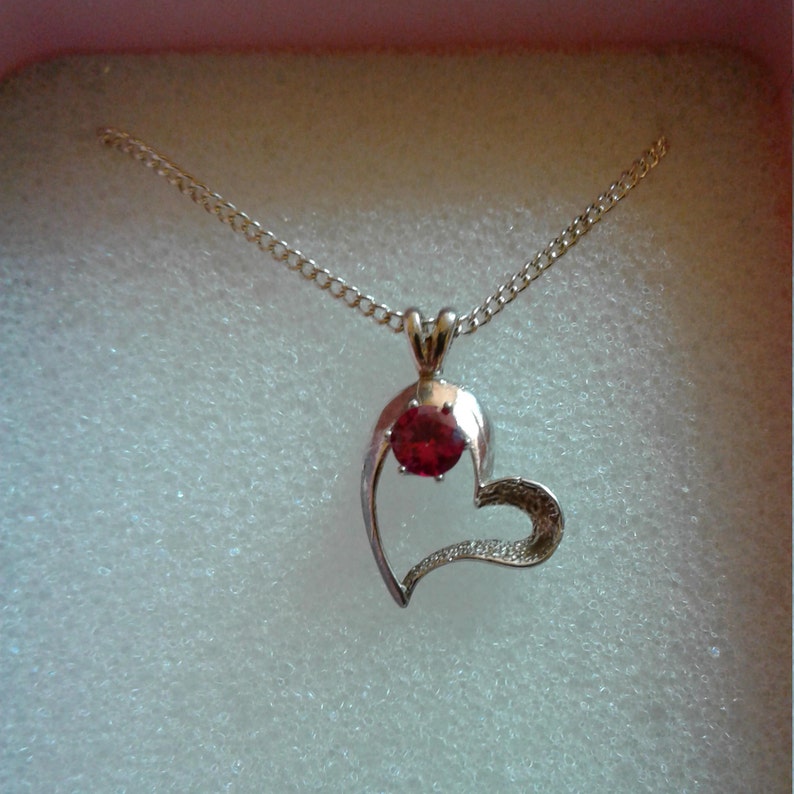 Sm womens or girl set in a silver heart and has a 16 silver chain with a 2 ext A 5mm round Ruby weighing.55 ct. Ruby Heart Pendant lab