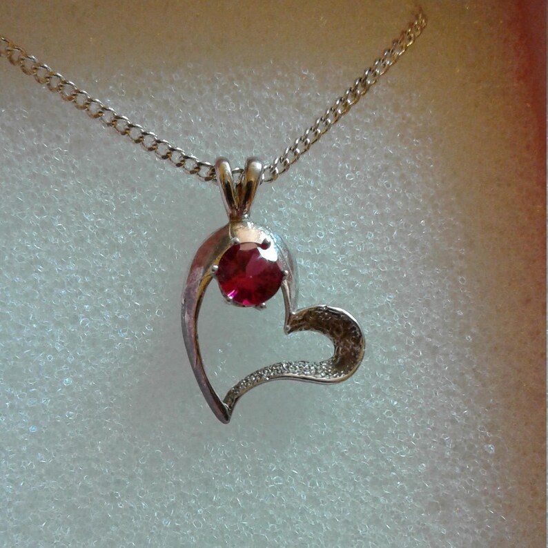 Sm womens or girl set in a silver heart and has a 16 silver chain with a 2 ext A 5mm round Ruby weighing.55 ct. Ruby Heart Pendant lab
