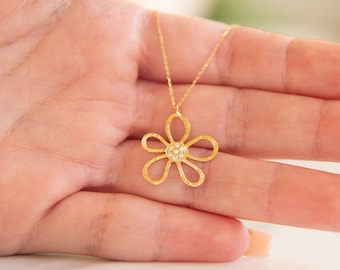 May include: A gold necklace with a delicate flower pendant featuring a cluster of small clear stones in the center.