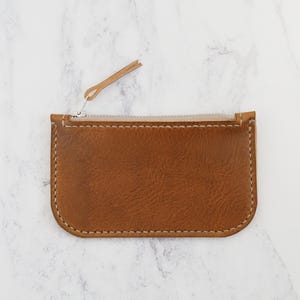 May include: A small brown leather zipper pouch with a light brown zipper pull.