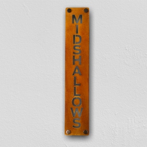 May include: A rusty metal sign with the word "MIDSHALLOWS" cut out in black lettering. The sign has four small black screws on each end.