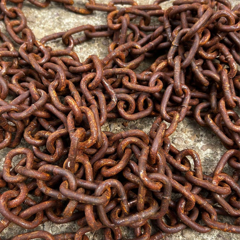 May include: Close-up of a pile of rusty metal chains. The chains are a deep reddish-brown color, with visible rust and wear. The links are interlocked, creating a dense, textured pattern. The image suggests a vintage or industrial theme.